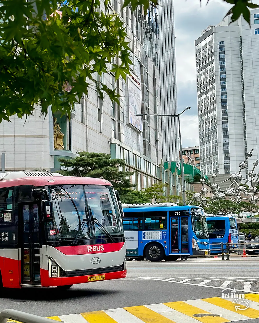 Autobuses urbanos rojos y azules circulando por una avenida de Seúl.