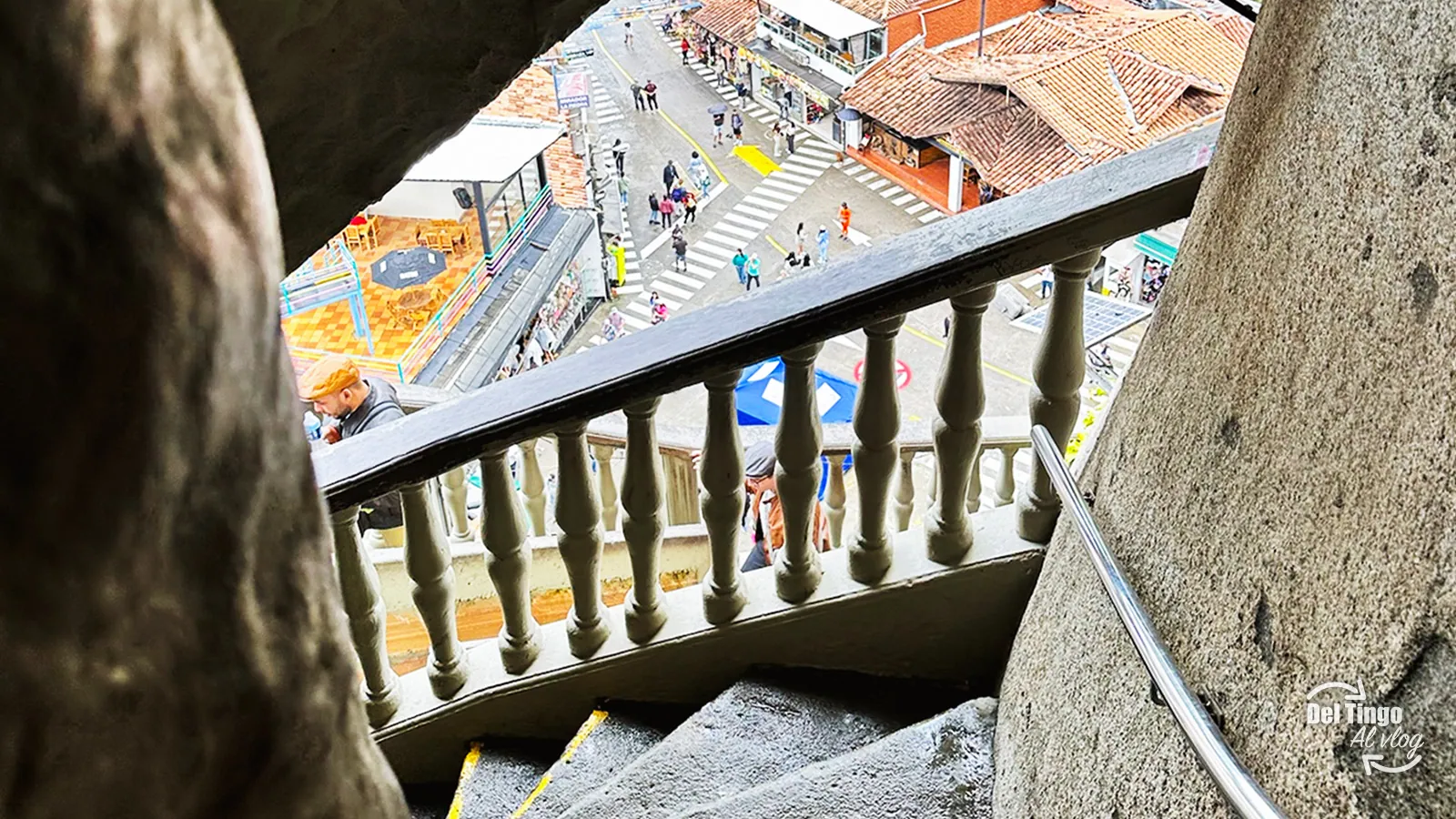 Vista de la zona comercial al pie de la Piedra del Peñol desde una de las plataformas intermedias, con barandal de cemento y techos rojos abajo