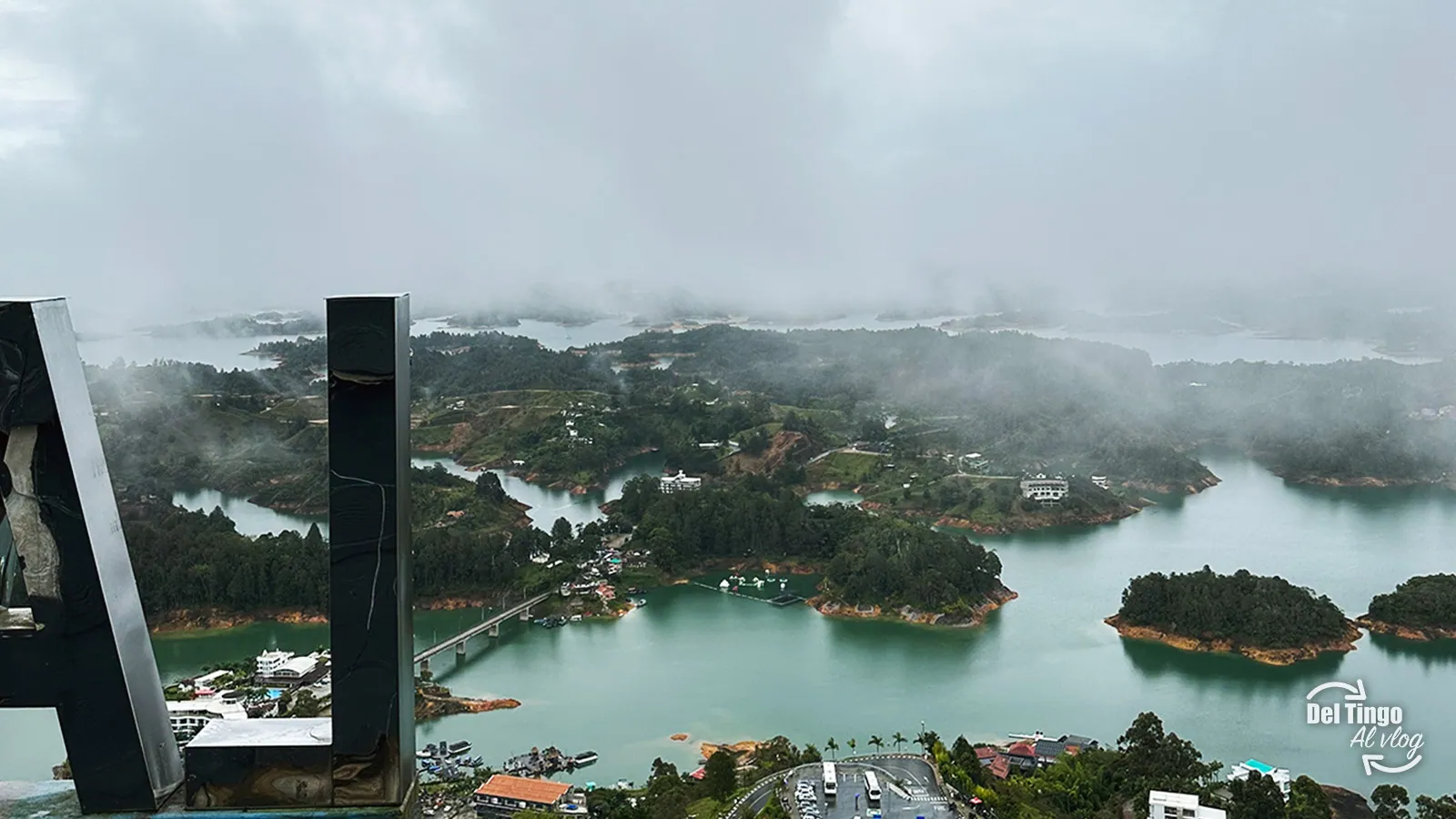 Vista panorámica desde la cima de la Piedra del Peñol al embalse de Guatapé con sus islas verdes, agua turquesa y niebla baja sobre el paisaje