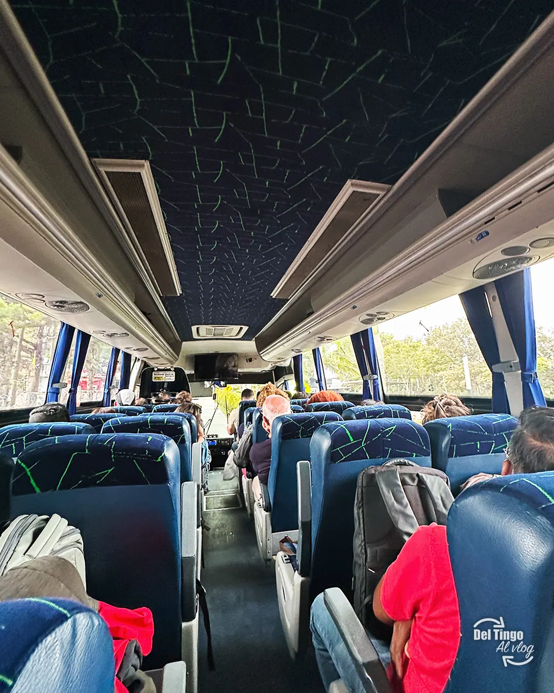 Interior del autobús turístico que sale desde Medellín hacia Guatapé, con sus asientos azules y pasajeros sentados al inicio del trayecto
