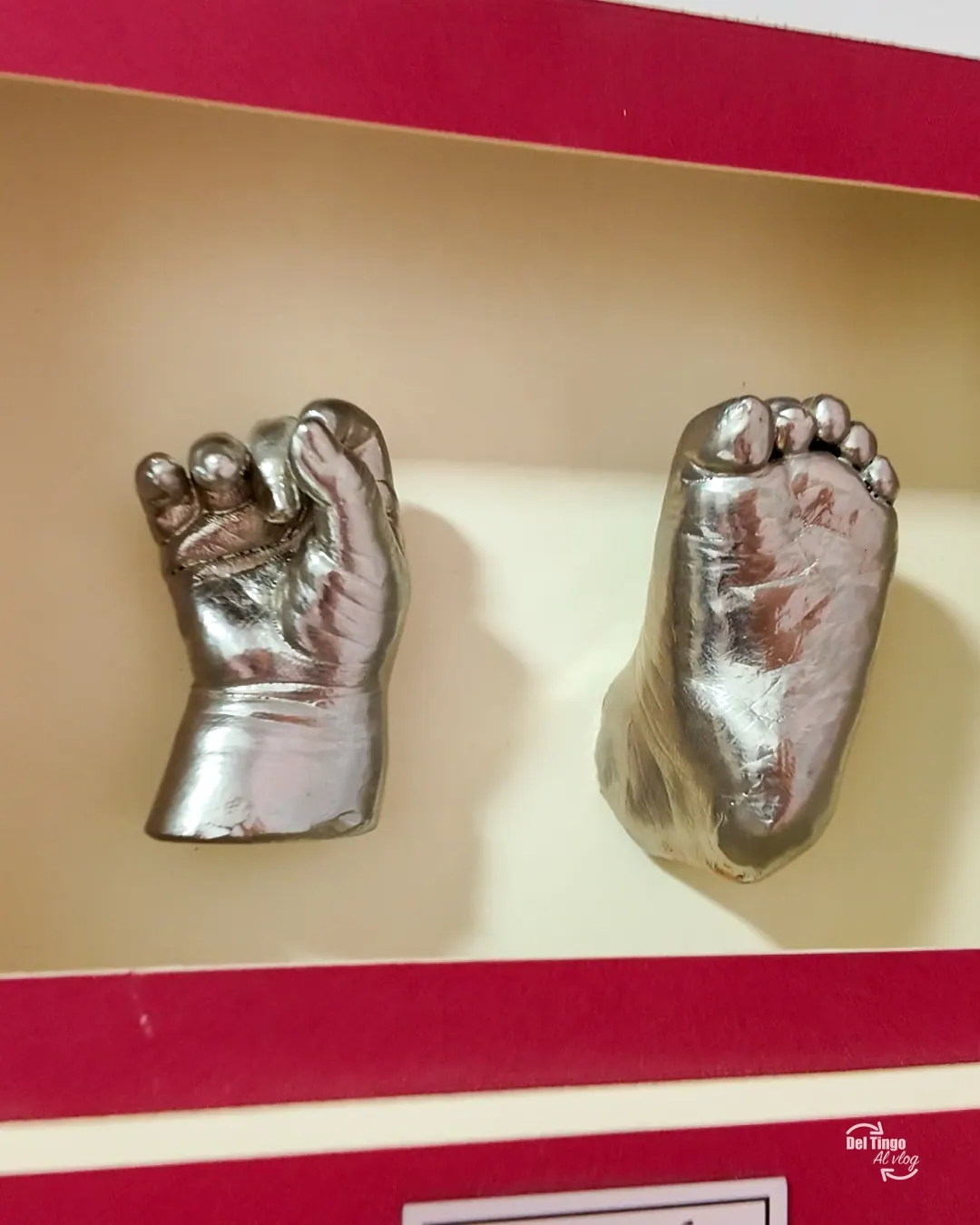 Una escultura terminada y enmarcada, con el molde de la mano y el pie