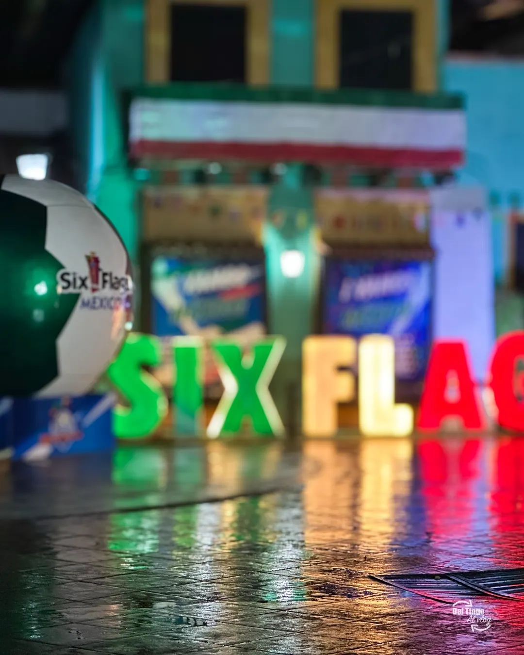 Letras de Six Flags y reflejos sobre el piso mojado de noche