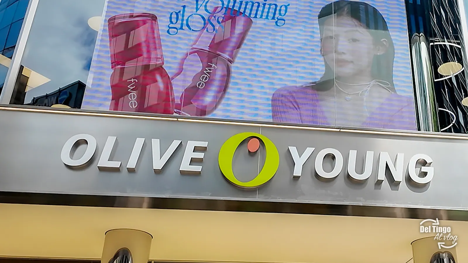 Fachada de la tienda Olive Young en Myeongdong, Seúl, con su logotipo blanco y pantalla publicitaria de productos de K-beauty