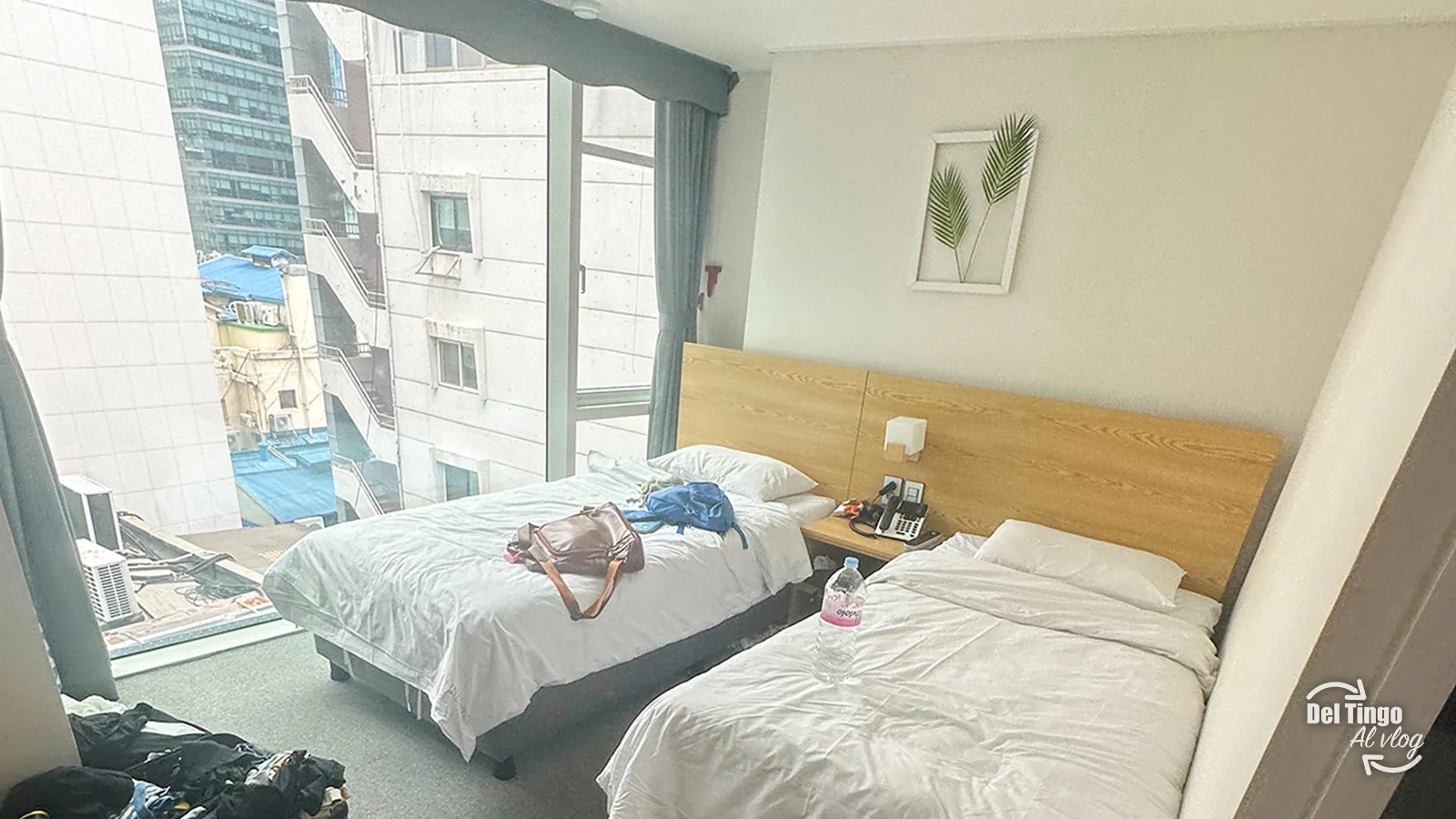 Habitación con dos camas, cabecera de madera y ventanal amplio con vista a los edificios de Myeongdong en el Line Hotel de Seúl