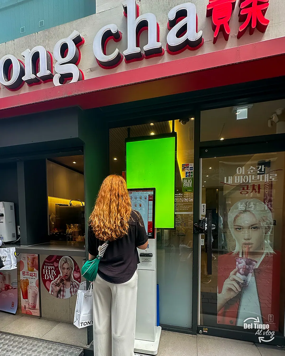 Clienta usando el kiosco de pantalla táctil para pedir su bebida en una sucursal de Gong Cha en Myeongdong, Seúl, con el letrero rojo de la tienda y carteles promocionales
