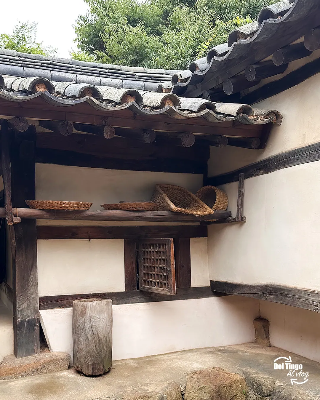 Casa tradicional coreana hanok en el National Folk Museum de Seúl, con techo de tejas grises, cestas tejidas y muros de barro blanco