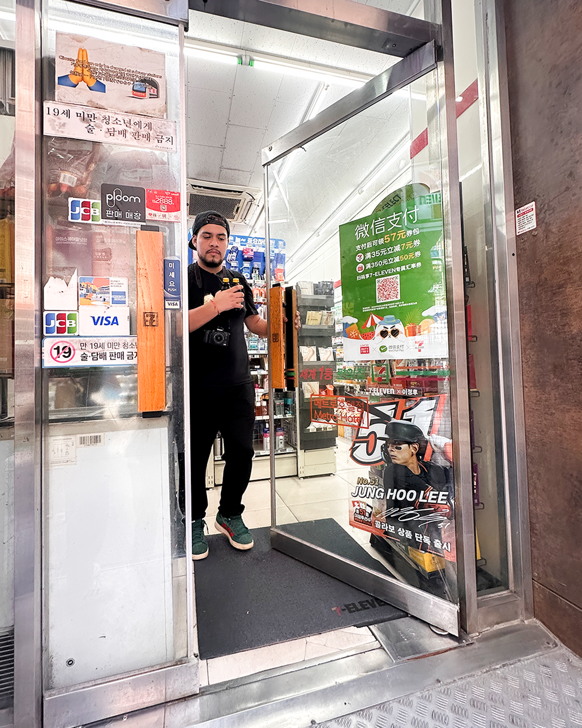 Viajero saliendo de un 7-Eleven en Myeongdong, Seúl, con varios productos en las manos